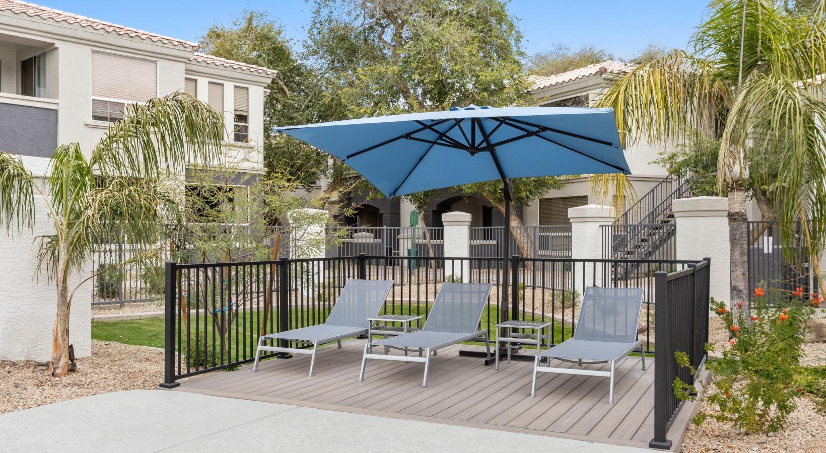 Relax and unwind poolside a patio with chairs and umbrella